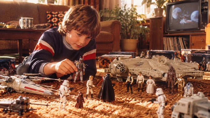 jongen van ongeveer 9 jaar ligt op een hoogpolig bruin vloerkleed te spelen met vintages starwars speelgoed figuren
